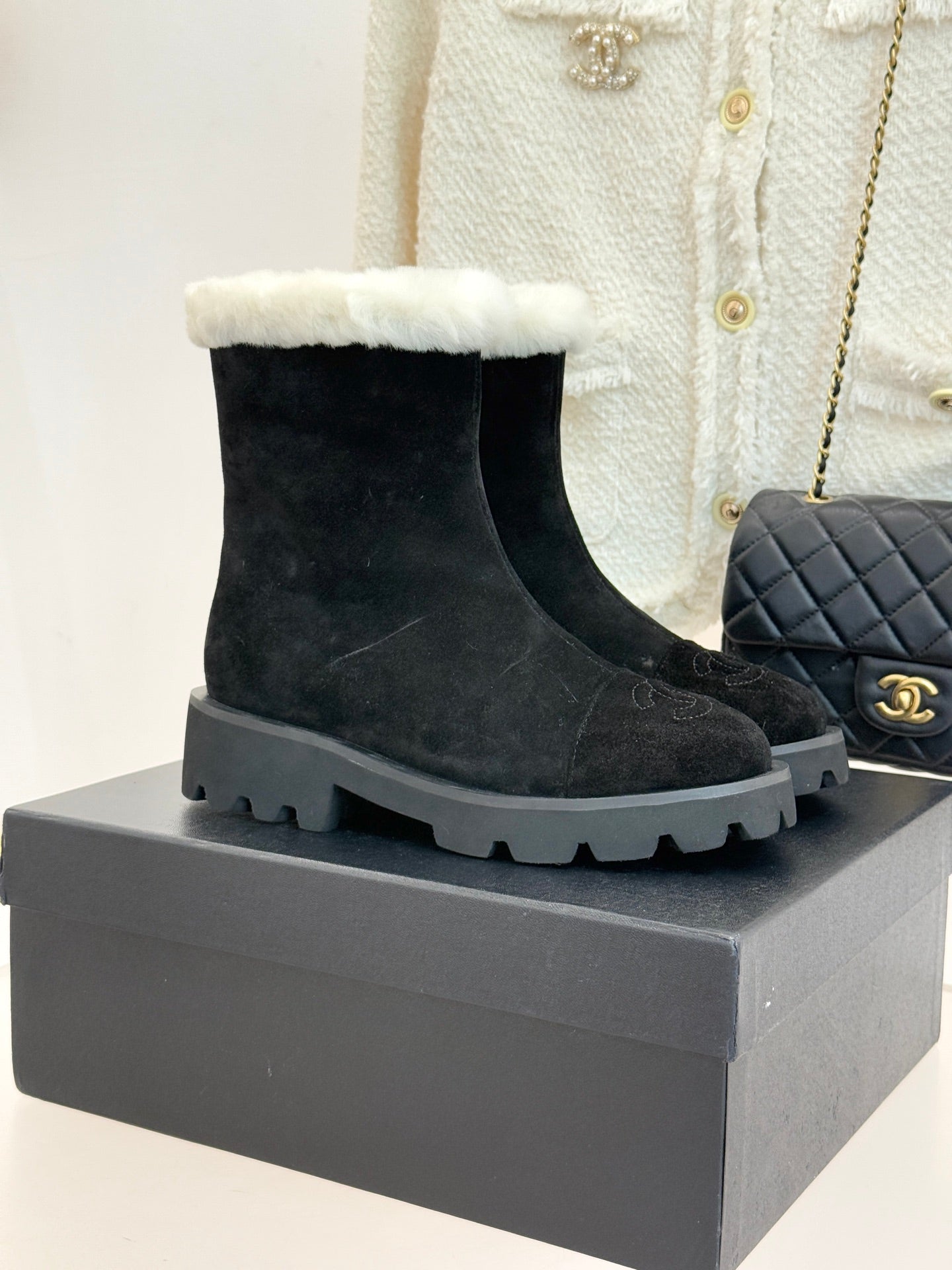 Black suede ankle boots with white shearling cuff and chunky gray lug sole