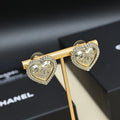 Gold-tone heart stud earrings on a gold holder with rhinestone outer trim