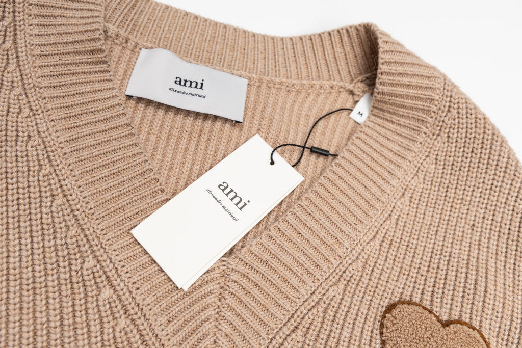 Beige knit sweater with Ami hang tags and ribbed V-neck detail