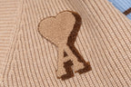 Beige knit sweater with brown heart applique and stitched monogram