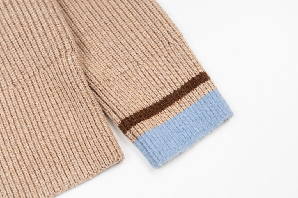 Beige knit sweater sleeve cuff with blue stripe and brown border