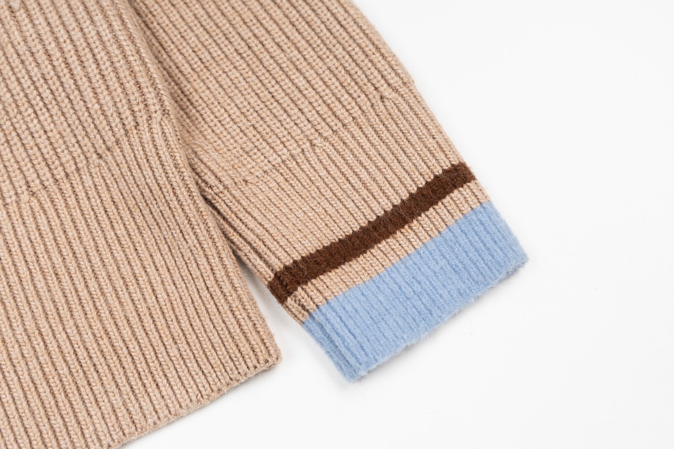 Beige knit sweater sleeve cuff with blue stripe and brown border