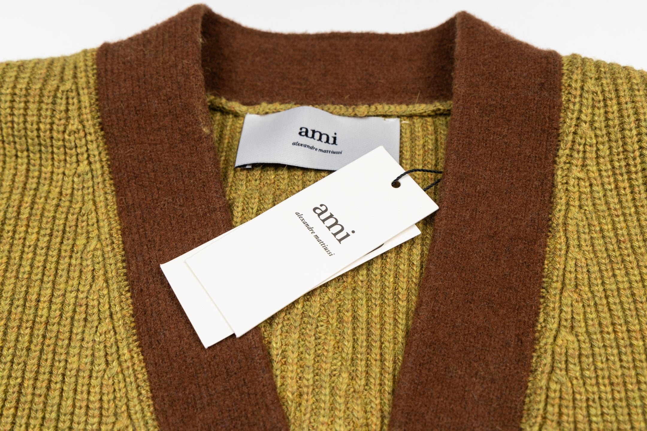Olive cardigan neckline with brown V-placket and tag at center front