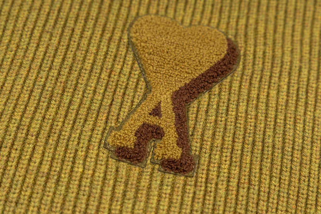 Embroidered bone patch detail on olive ribbed knit