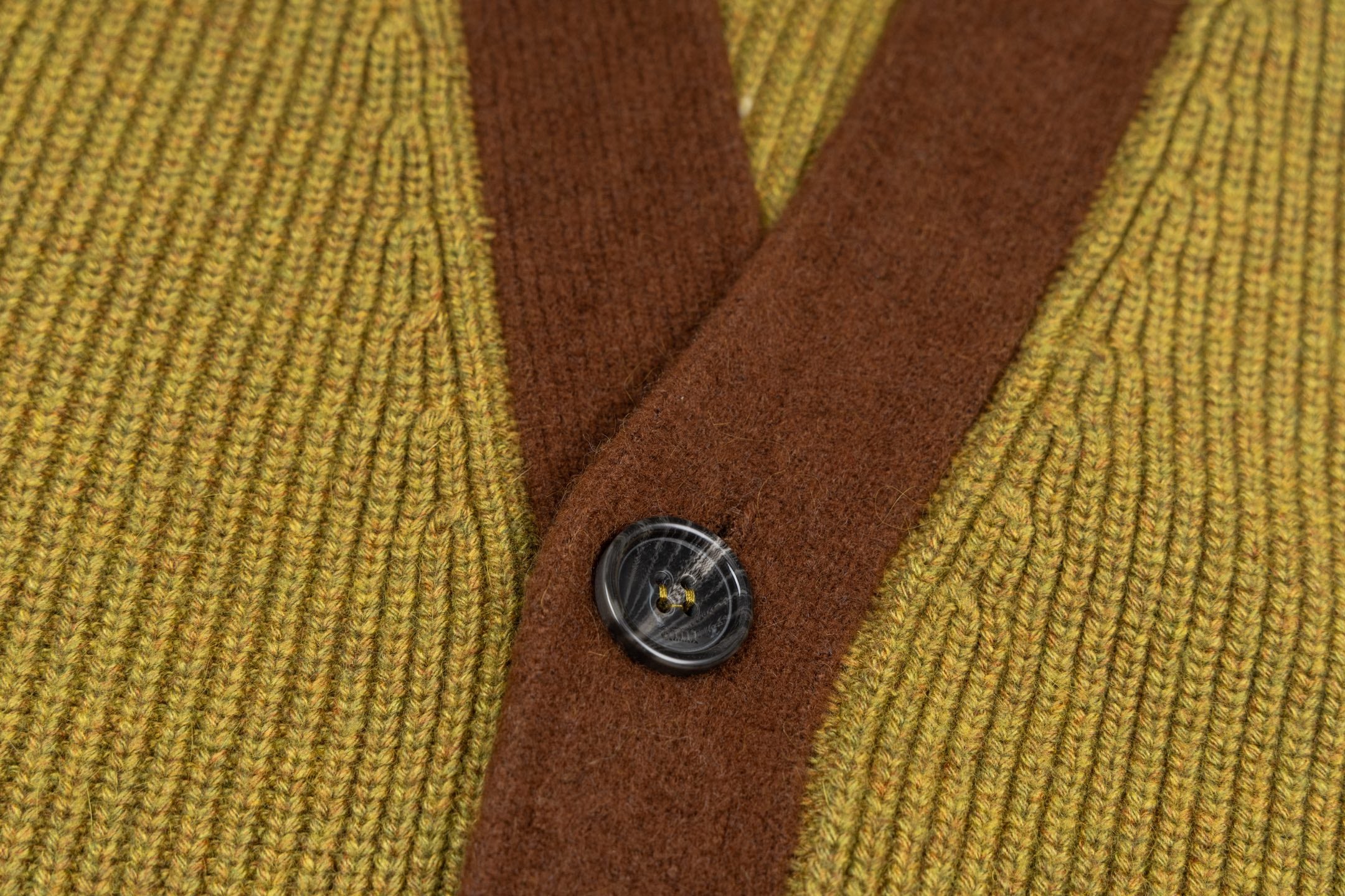 Brown button placket with four dark metal buttons on olive knit cardigan