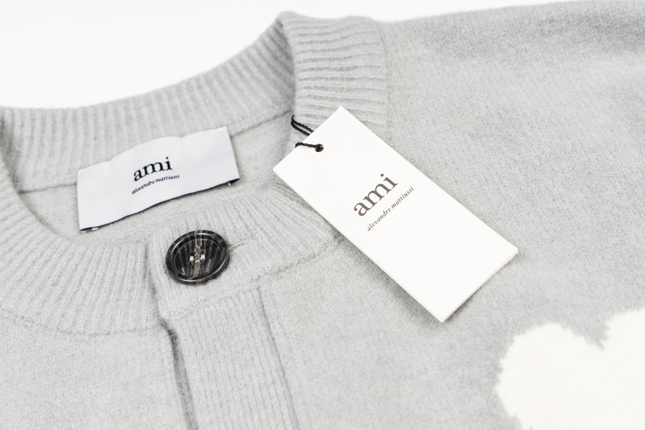 Light gray knit cardigan with button front, ribbed collar, and hang tag