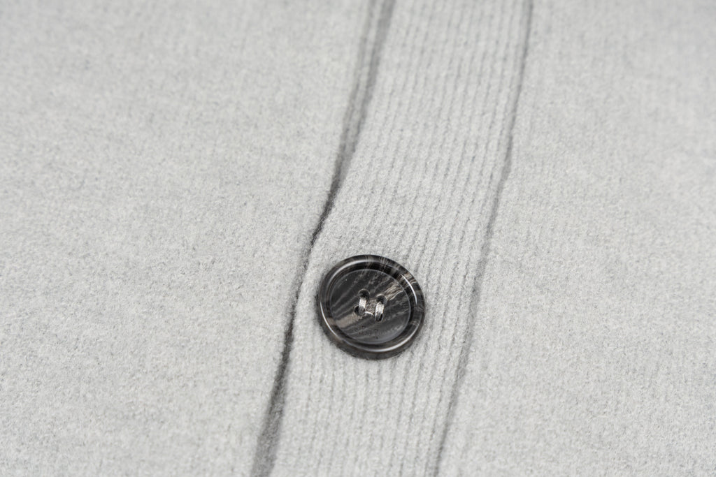 Light gray knit cardigan with round dark button on front placket