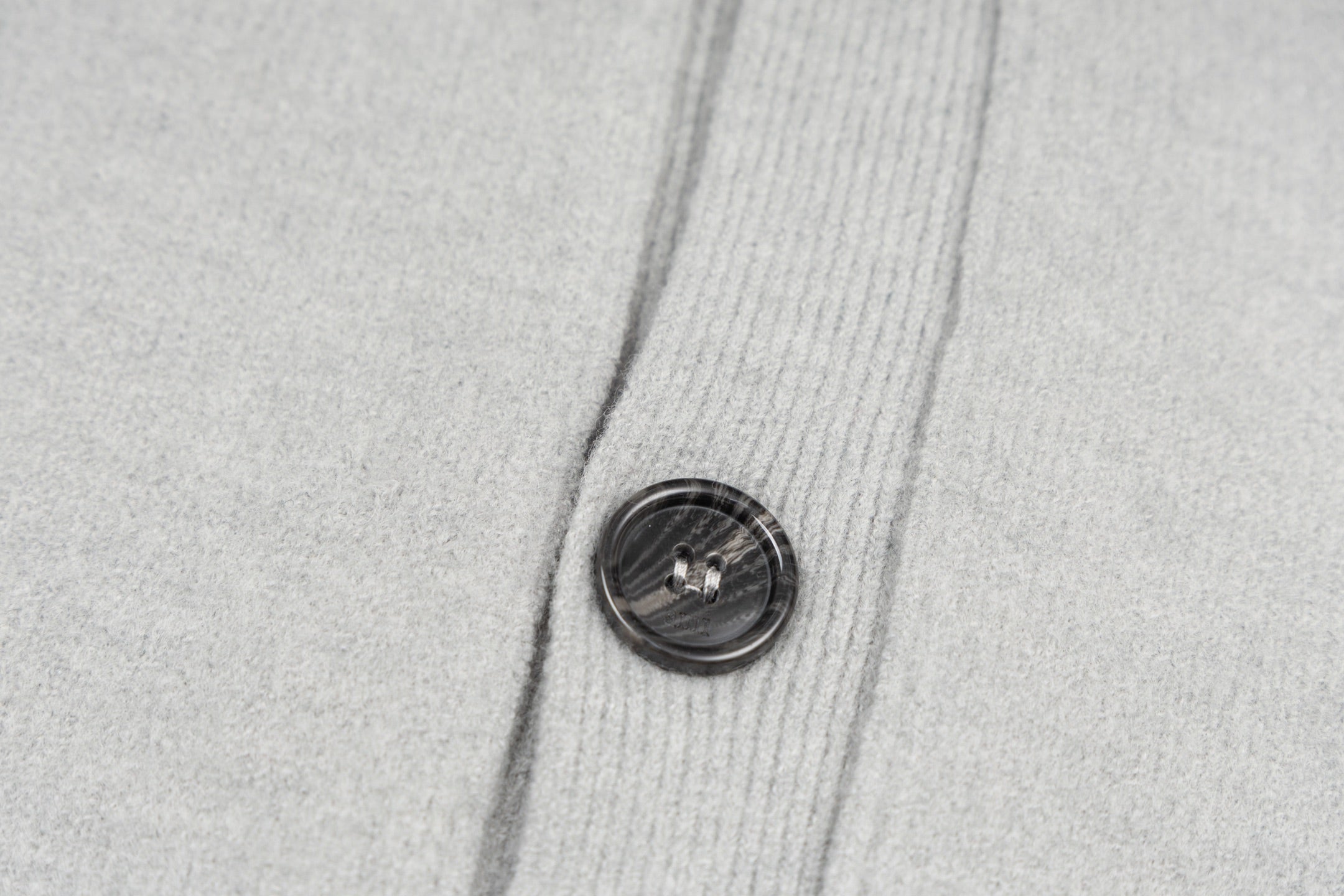Light gray knit cardigan with round dark button on front placket