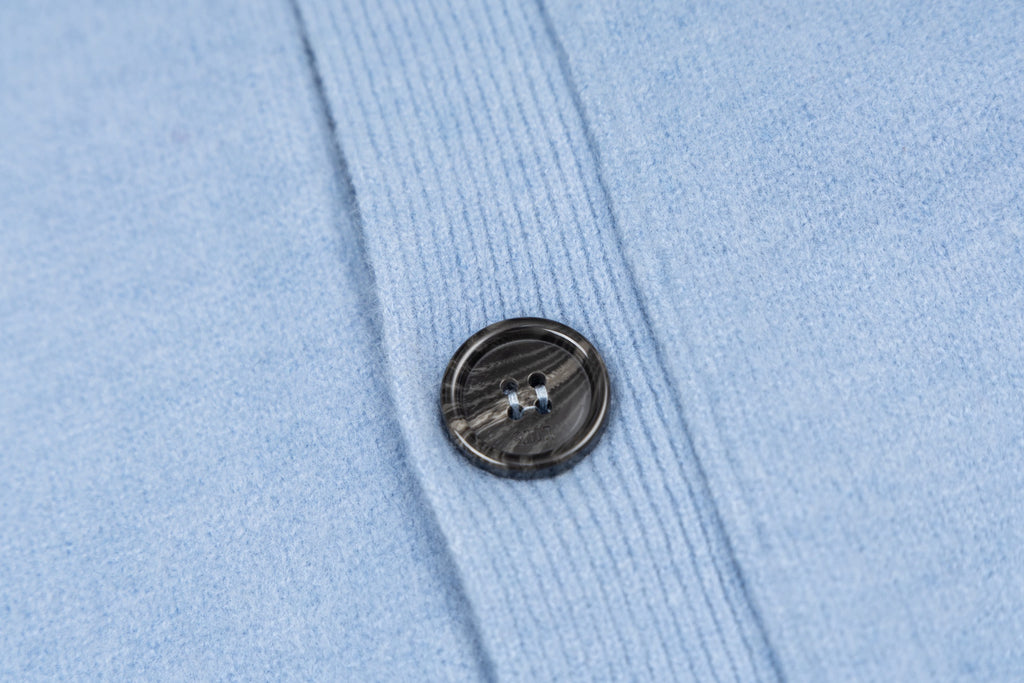 Amiri light blue knit cardigan close-up of black button on front placket