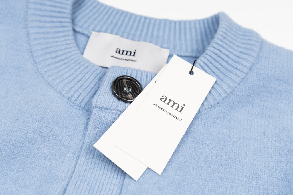 Amiri light blue knit cardigan with button placket, brand labels, and neck opening