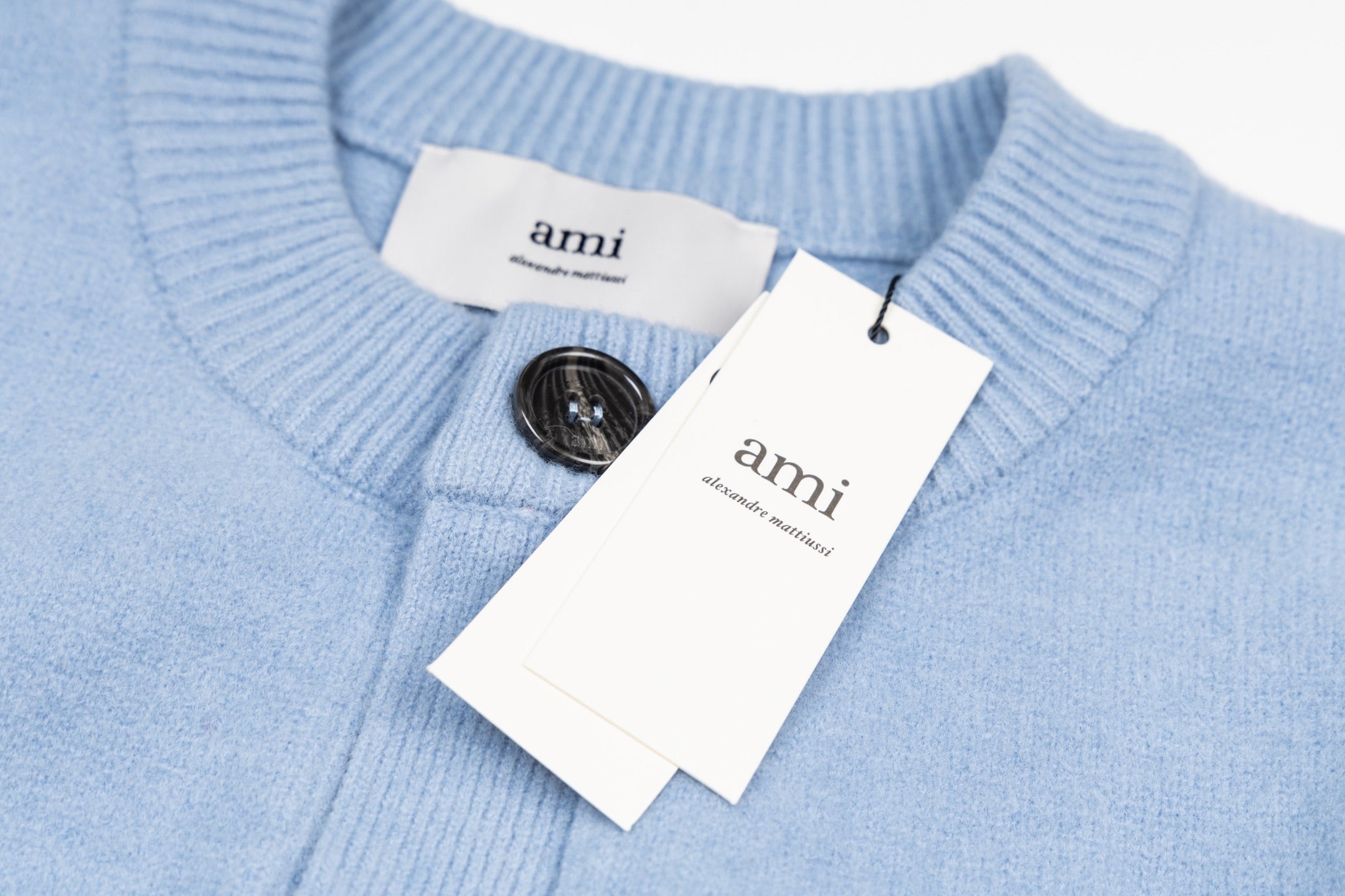 Amiri light blue knit cardigan with button placket, brand labels, and neck opening