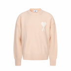 Light pink crewneck sweater with ribbed cuffs and hem, featuring a white heart logo
