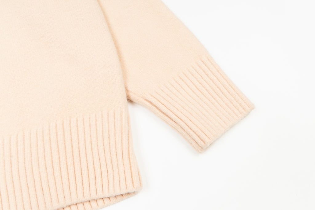 Light pink sweater cuff with ribbed knit texture at the sleeve hem