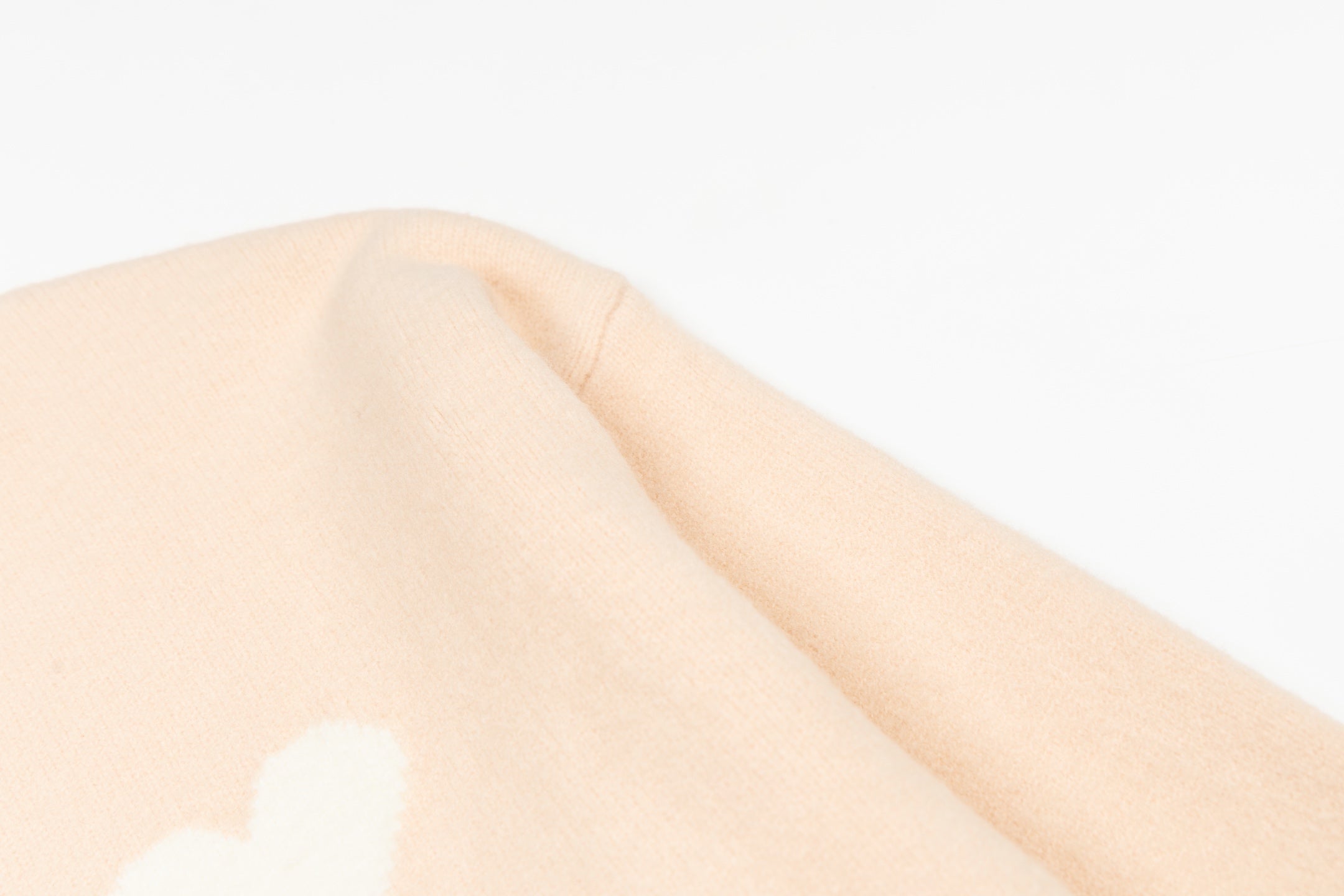 Light pink sweater with white heart-and-X motif on the upper sleeve
