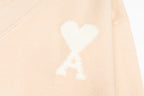 Amiri light peach cardigan with white heart logo motif on body