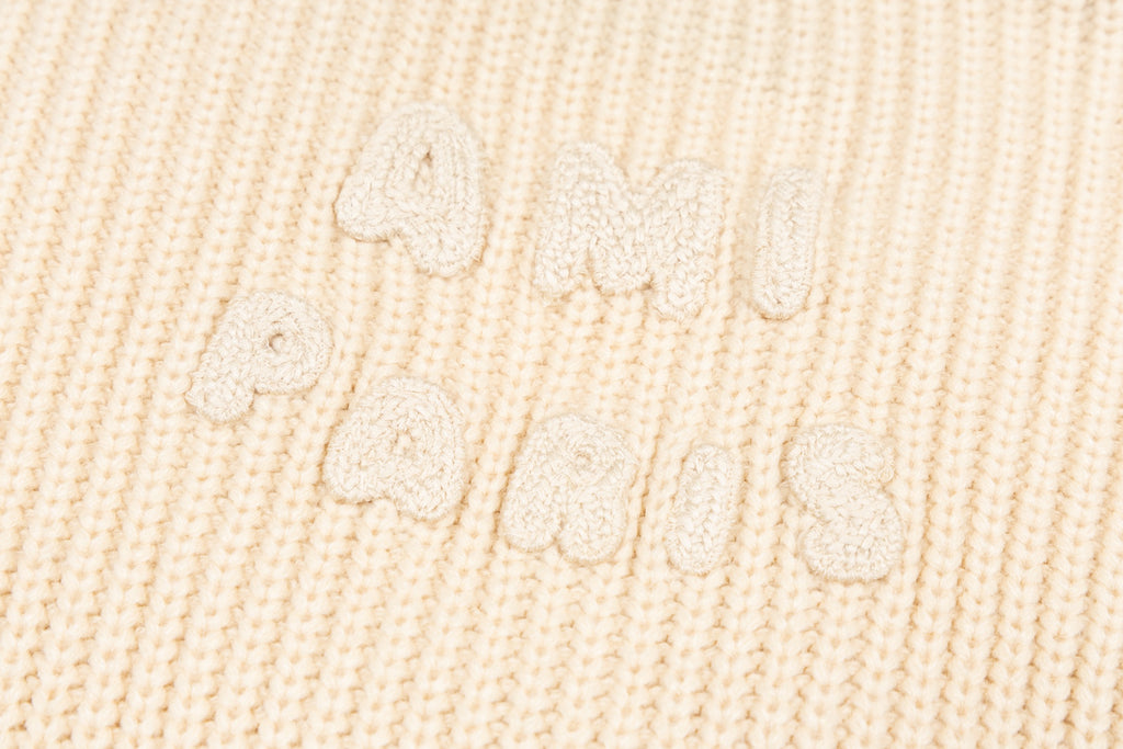 Cream knit sweater knit texture with raised embroidered script detail