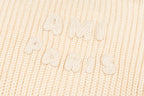 Cream knit sweater knit texture with raised embroidered script detail