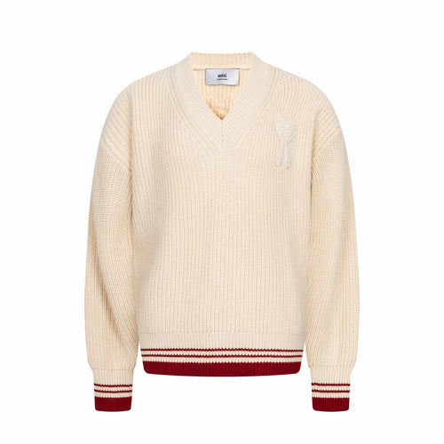 Cream knit sweater with V-neck and red-and-white striped ribbed hem and cuffs
