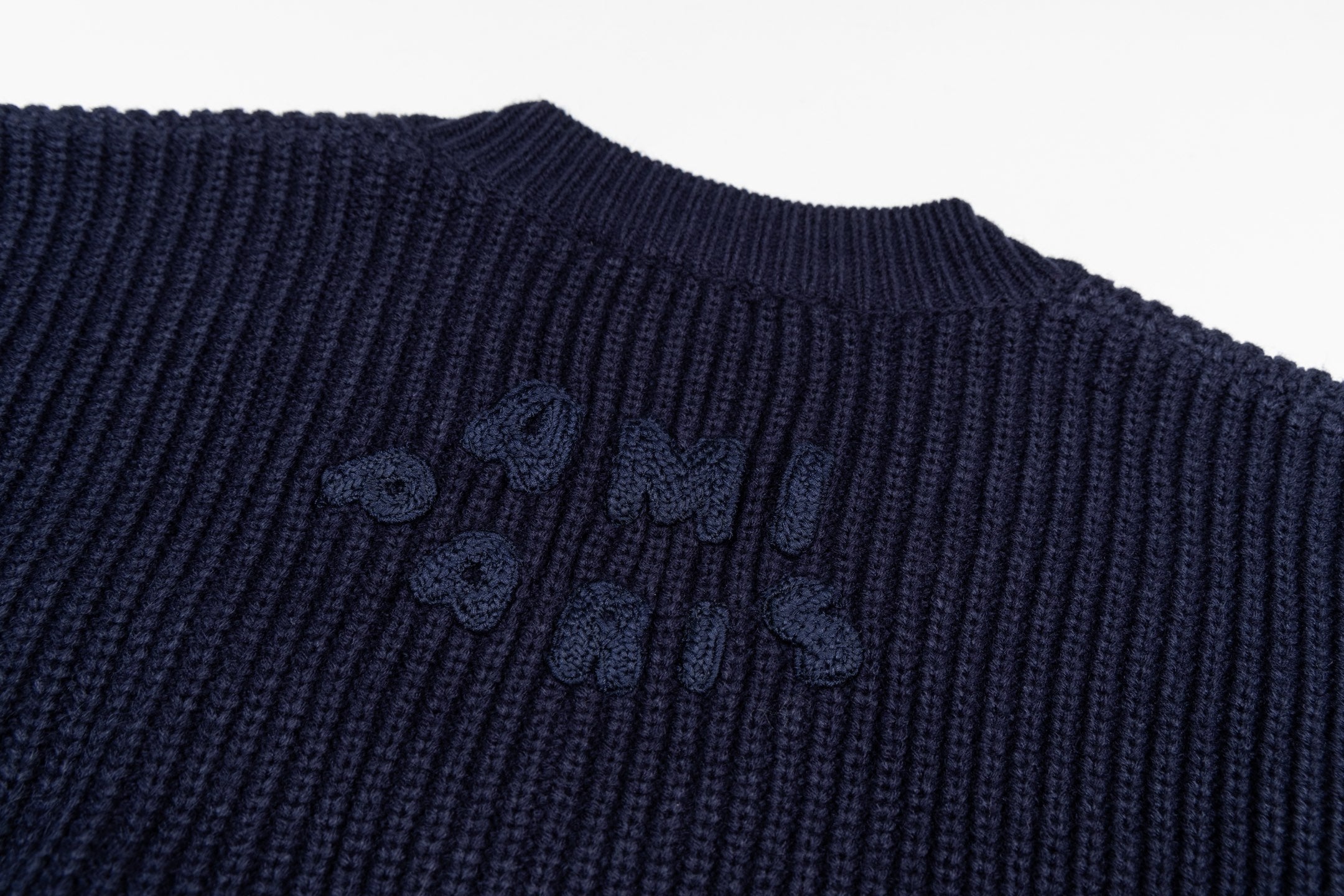 Navy knit sweater with dark embroidery logo across the chest
