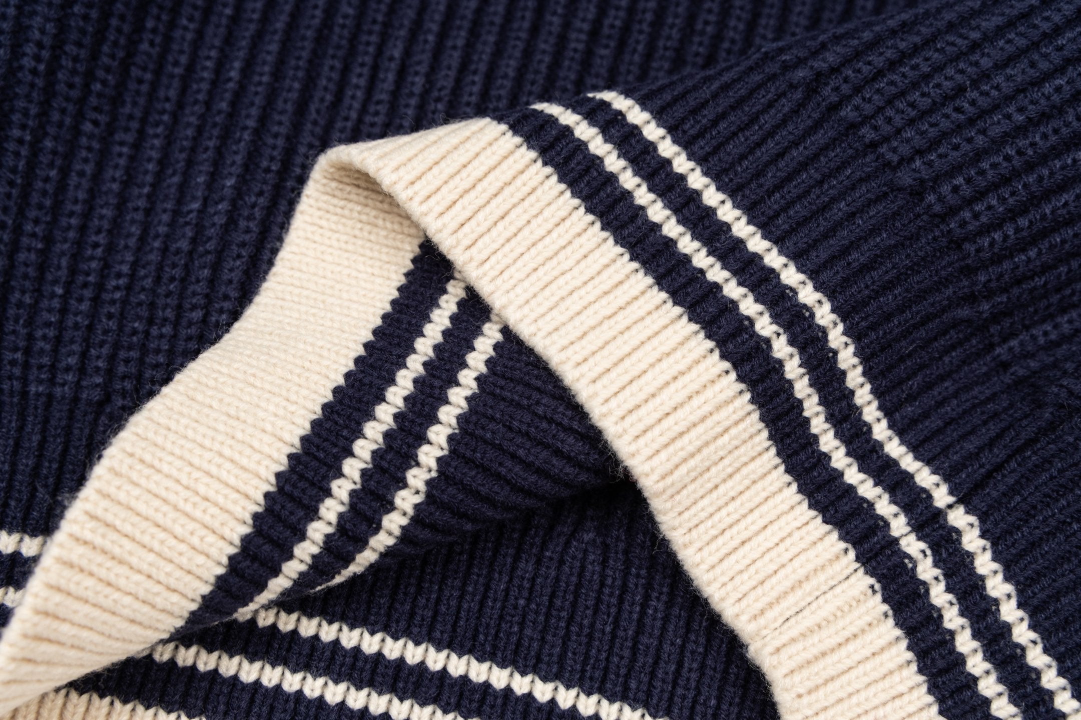 Navy knit sweater hem corner with cream and navy double stripe trim