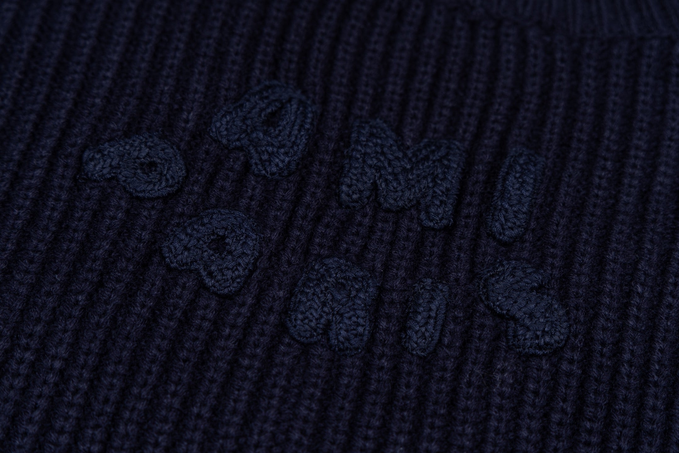 Navy ribbed knit sweater with embroidered motif on the knit panel