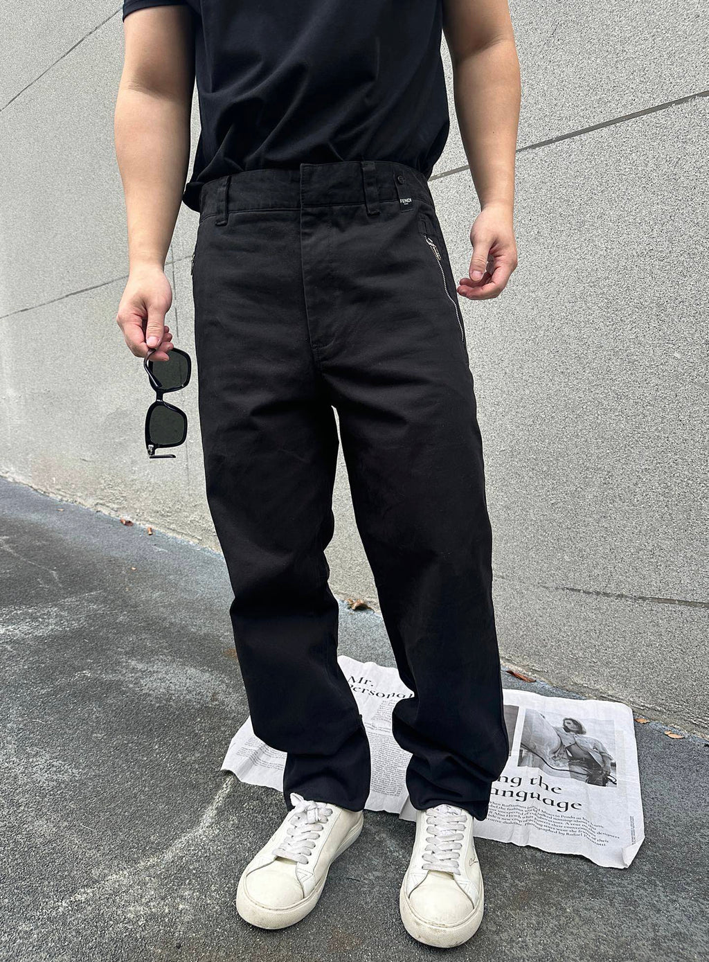 Close-up of black pants with belt loops, front pockets, and tapered cuffs