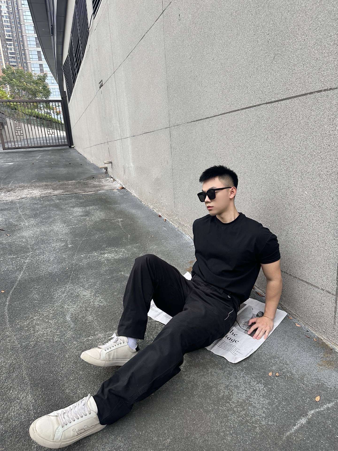 Black tapered pants in a seated pose with side pocket and cuffed hem