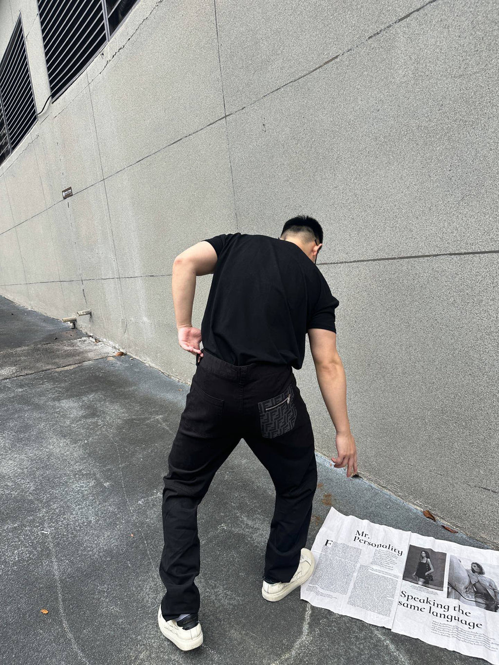 Back view of black tapered cargo-style pants with side pocket and cuffed hem