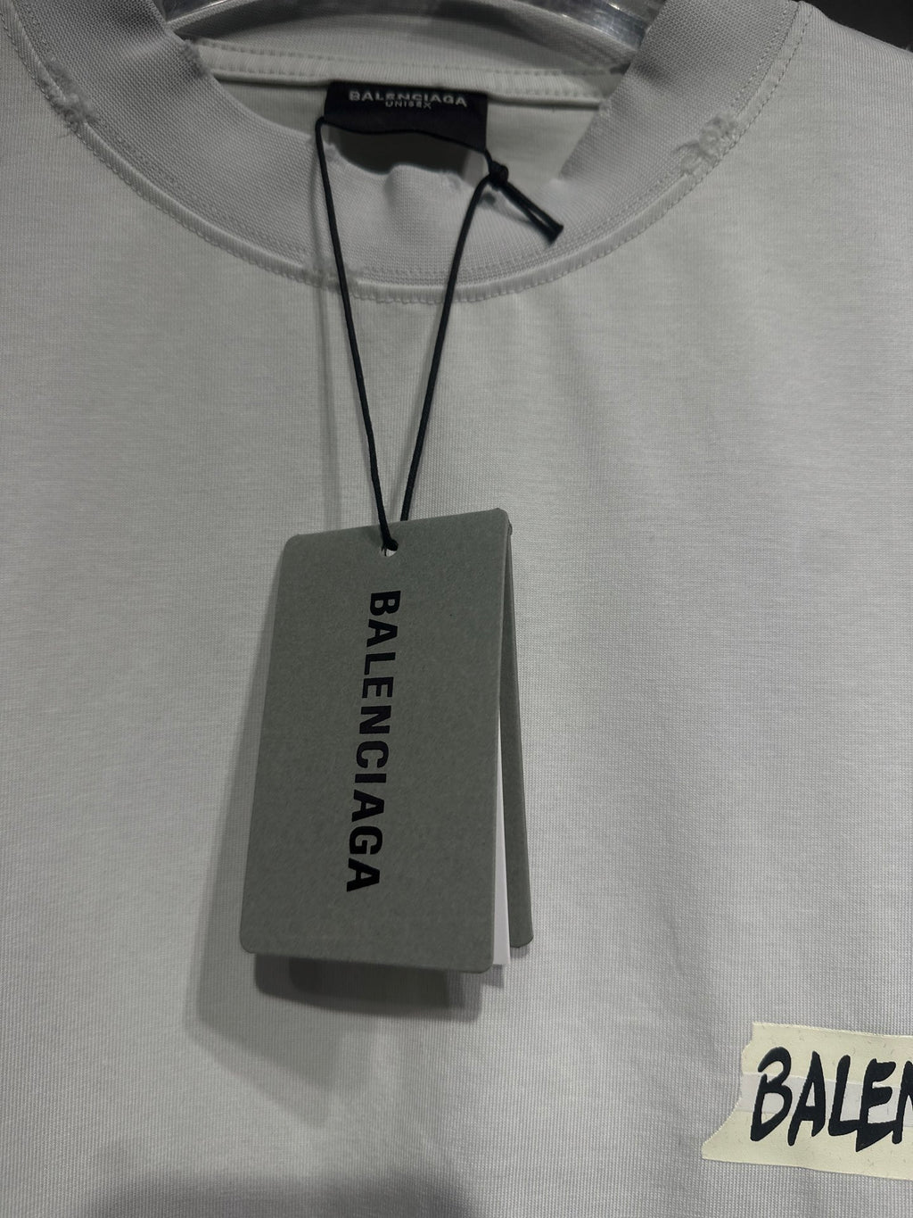White Balenciaga T-shirt neckline close-up with hanging tag above logo