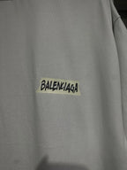 White Balenciaga T-shirt chest close-up with black logo text on yellow patch