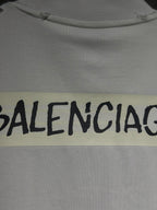 White Balenciaga T-shirt fabric close-up with black logo text on yellow patch