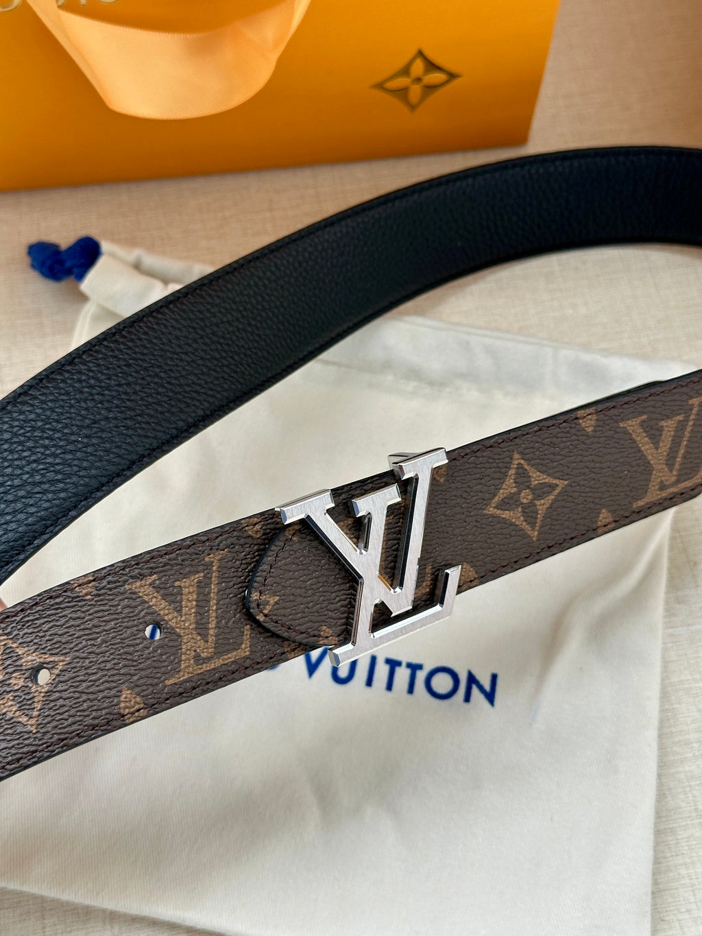 Dark monogram leather belt close-up with silver-toned LV buckle.