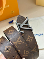Dark monogram leather belt detail with silver-toned LV buckle and punched holes.