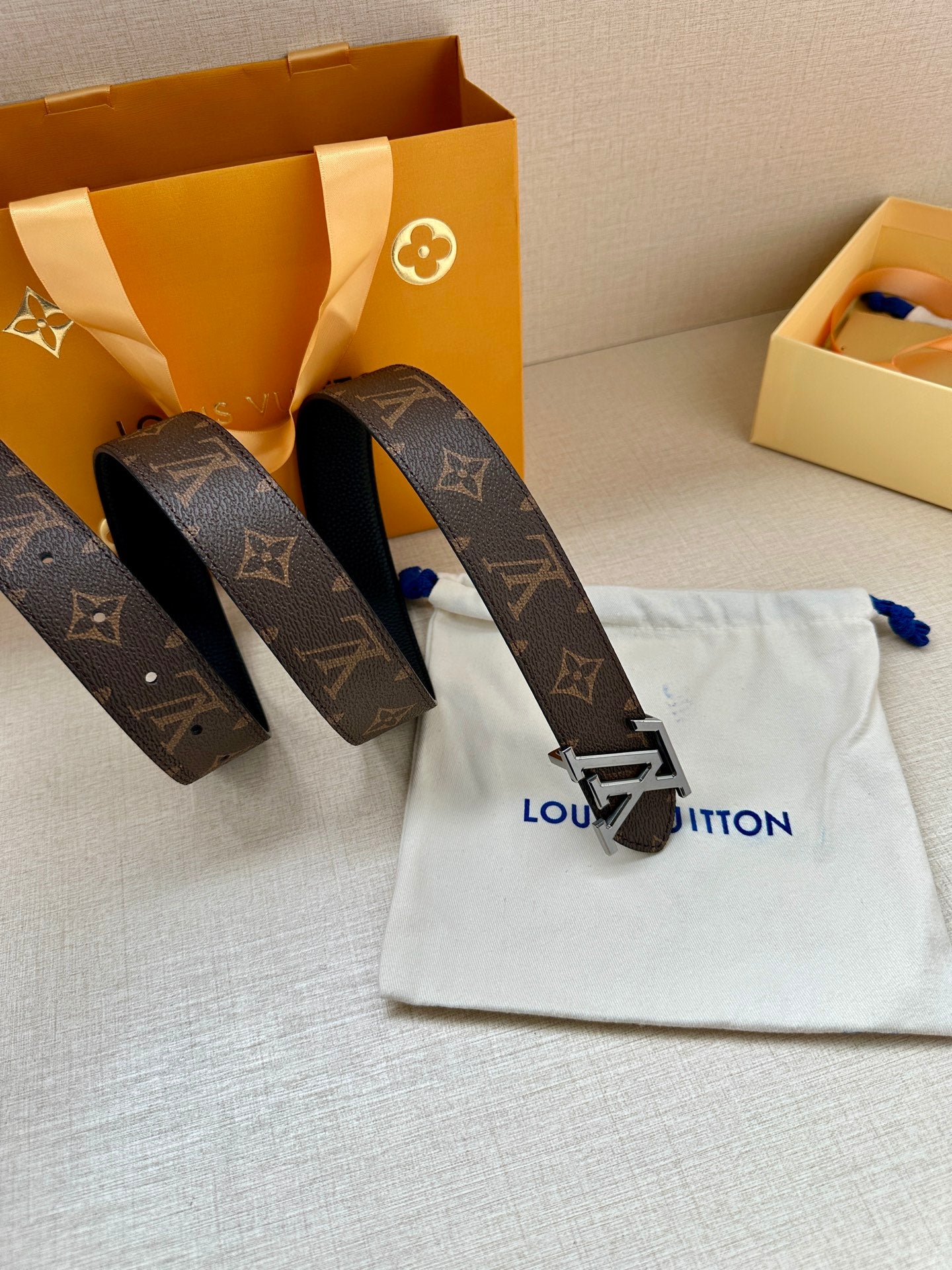 Dark monogram leather belt with silver-toned LV buckle and belt strap detail.