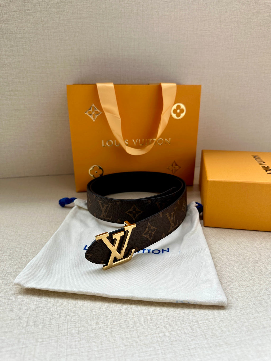 Dark monogram leather belt on white pouch with silver-toned LV emblem buckle.