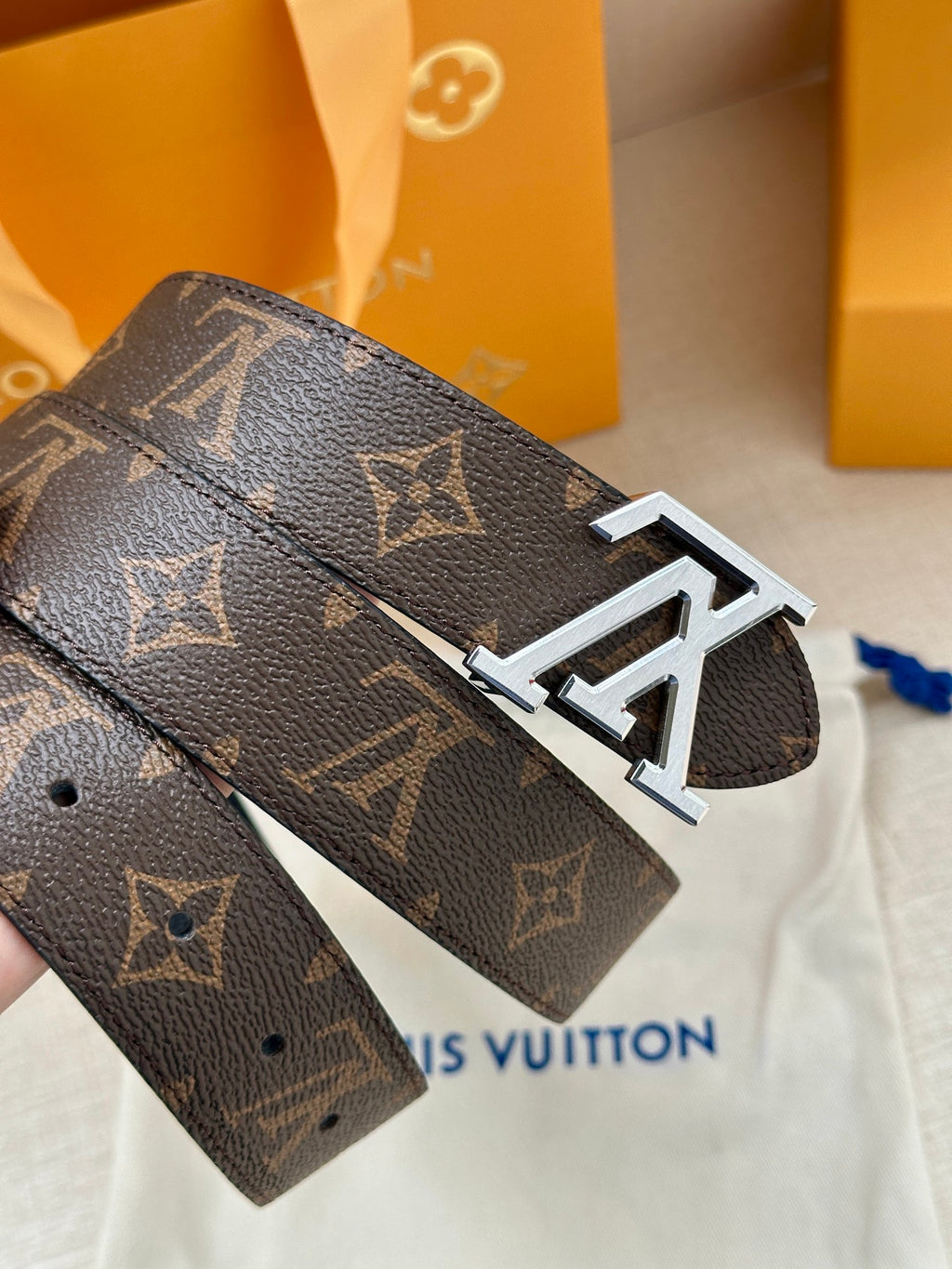 Dark monogram leather belt with silver-toned LV buckle, angled view.