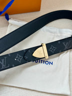 Close-up monogram belt strap with textured leather edge and gold-tone buckle