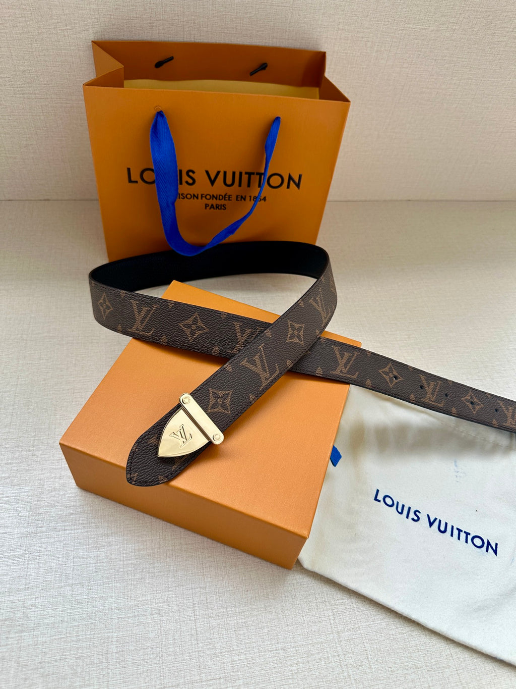 Louis Vuitton belt with dark brown monogram strap and silver buckle, folded in front