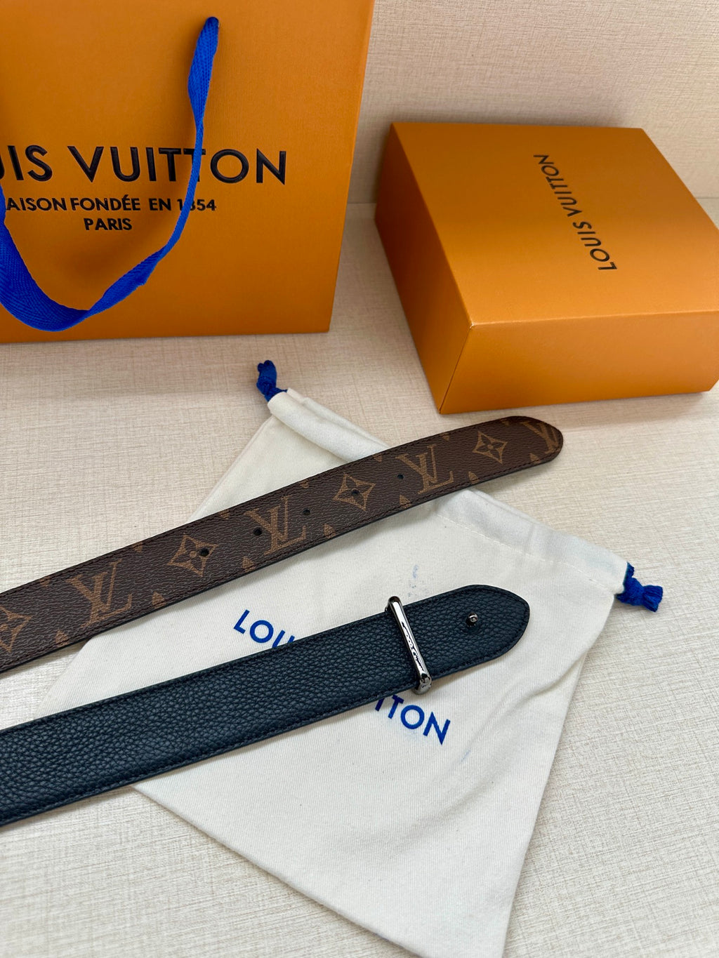 Louis Vuitton belt laid flat: dark brown monogram strap with silver buckle