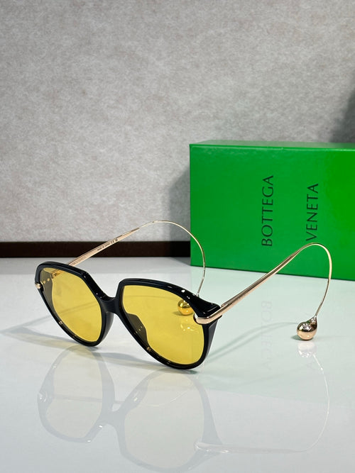 Bottega Veneta sunglasses with black frames and yellow-tinted lenses, gold-tone arms