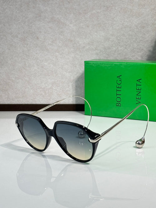 Bottega Veneta sunglasses with black frames and dark blue-gray lenses, gold-tone arms