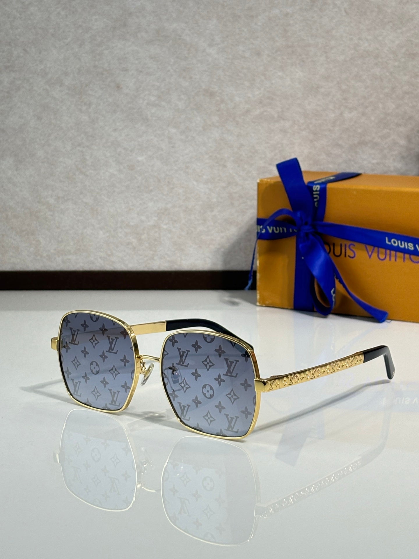 Gold-tone square sunglasses with light blue logo print lenses and textured temple arms