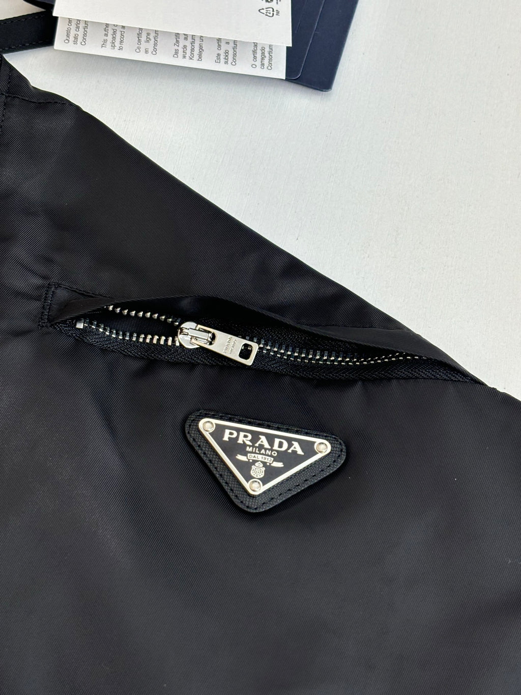 Prada black jacket front detail with metal zipper pull and triangular logo patch