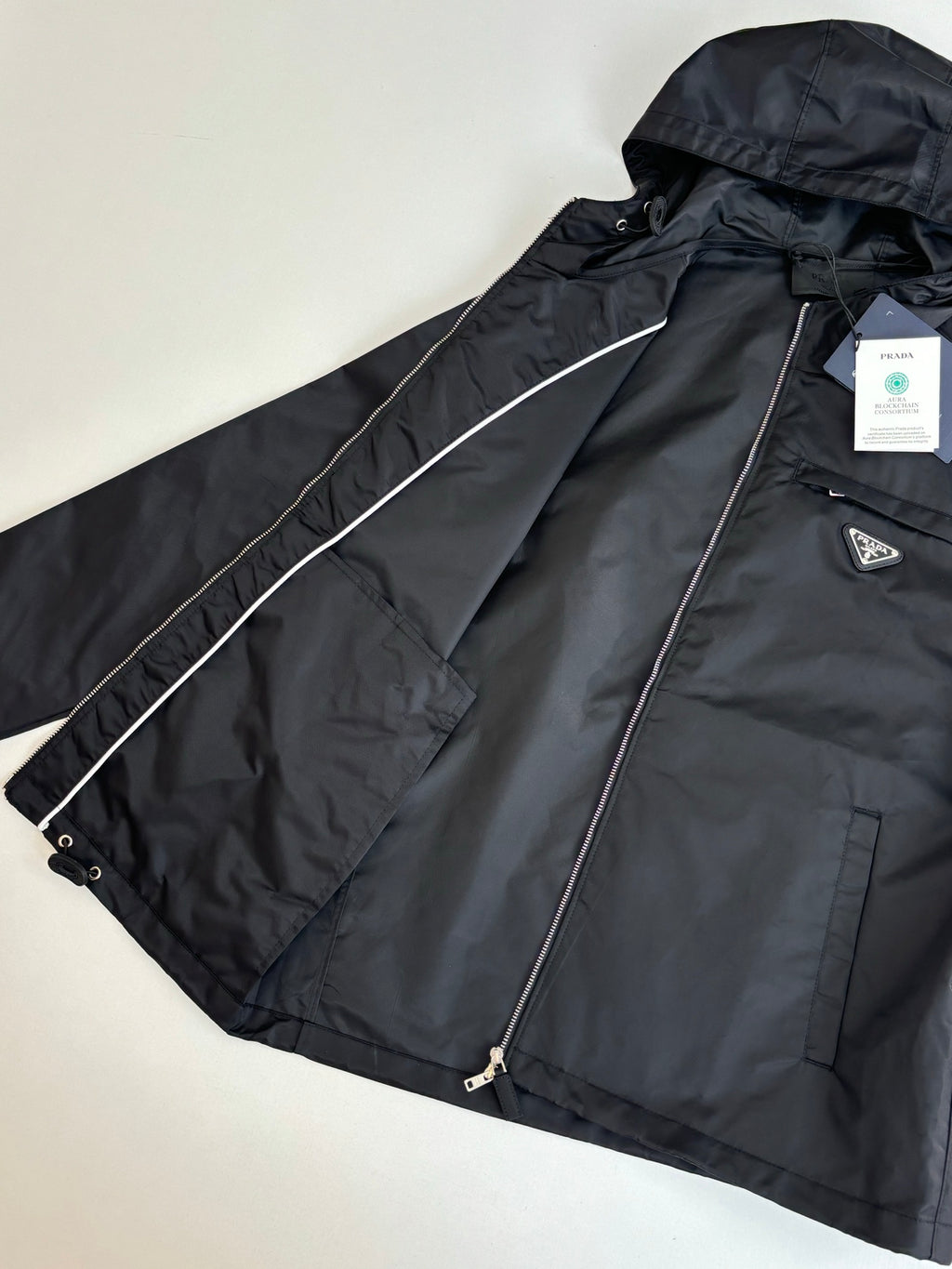 Prada black long hooded jacket with zip front, chest pocket, and logo patch