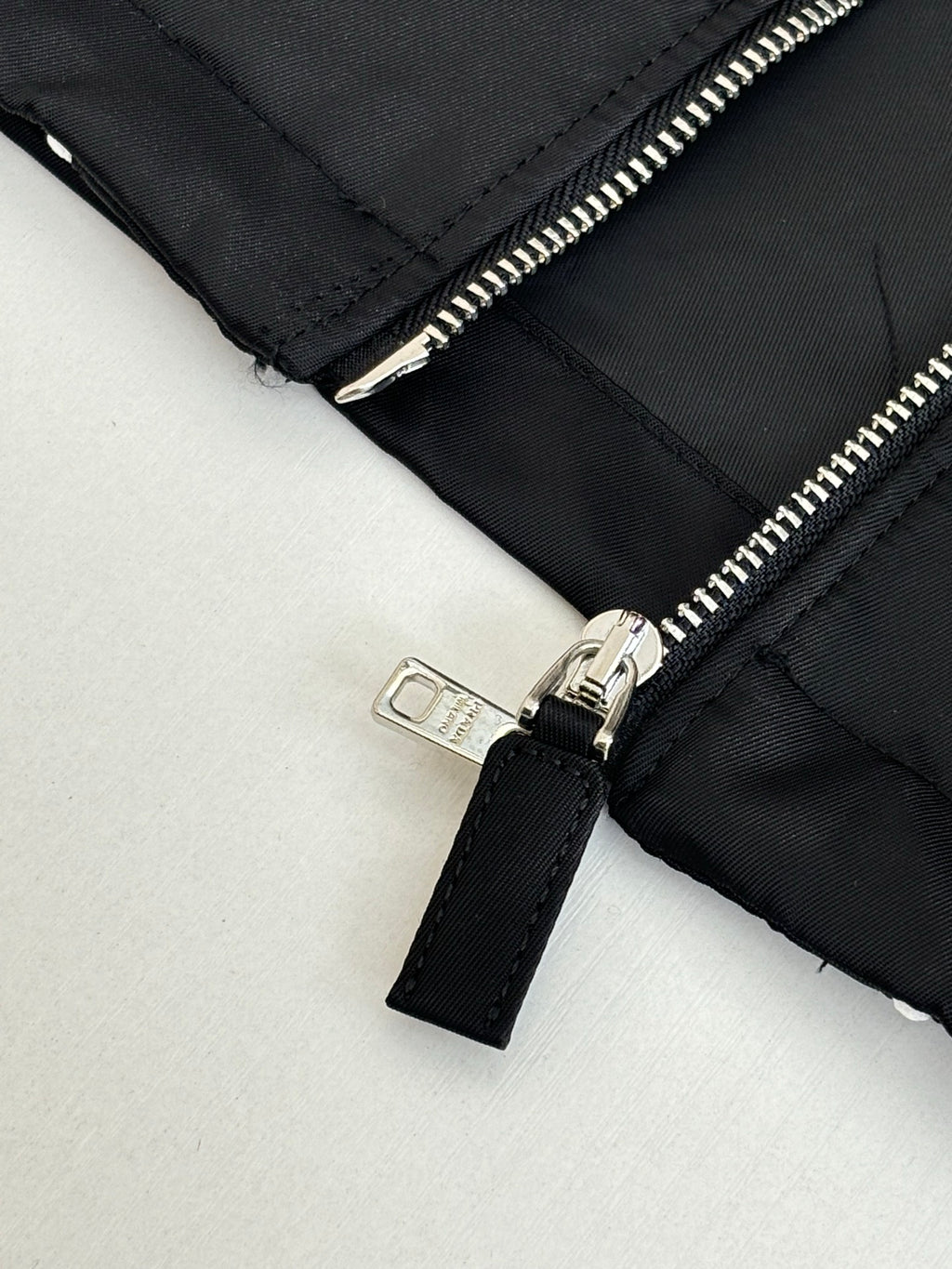 Prada black jacket sleeve detail with silver zipper and fabric pull tab