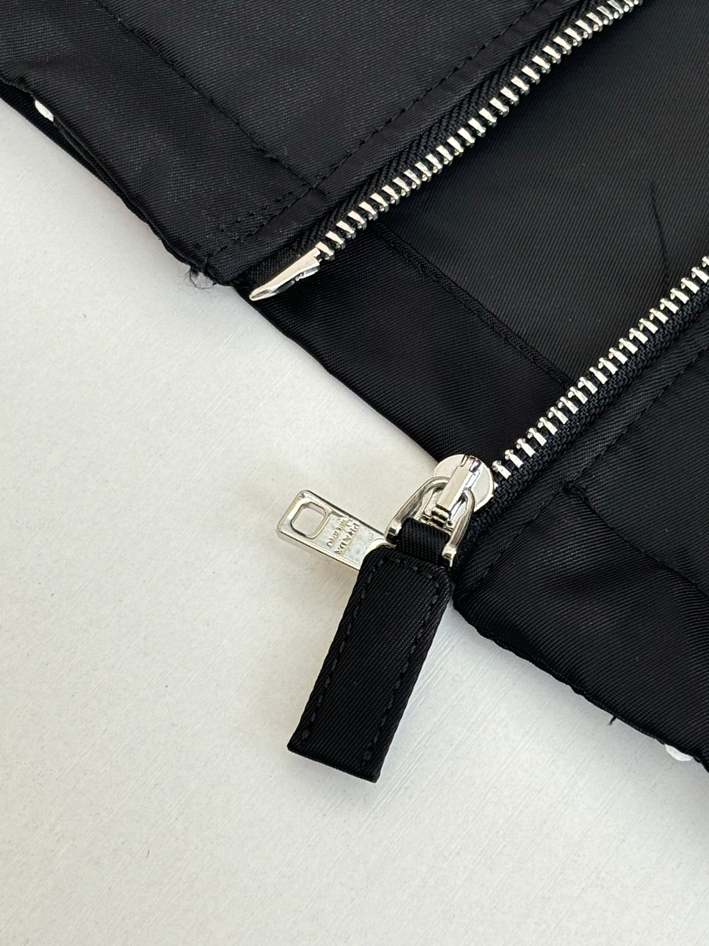 Prada black jacket sleeve detail with silver zipper and fabric pull tab