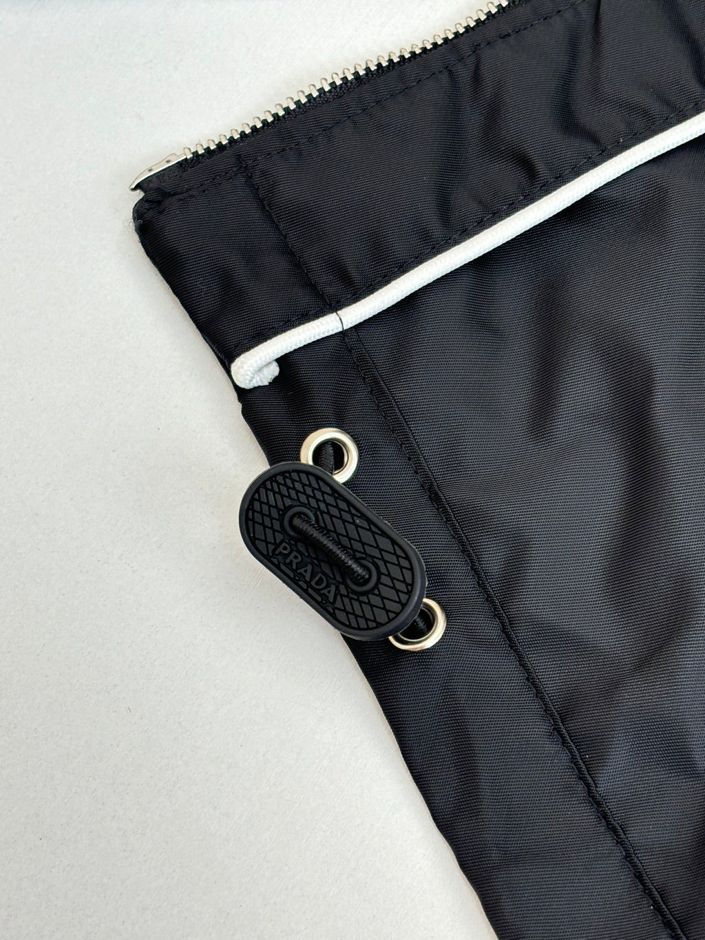 Prada black jacket pocket detail with snap closure and black logo keychain tag