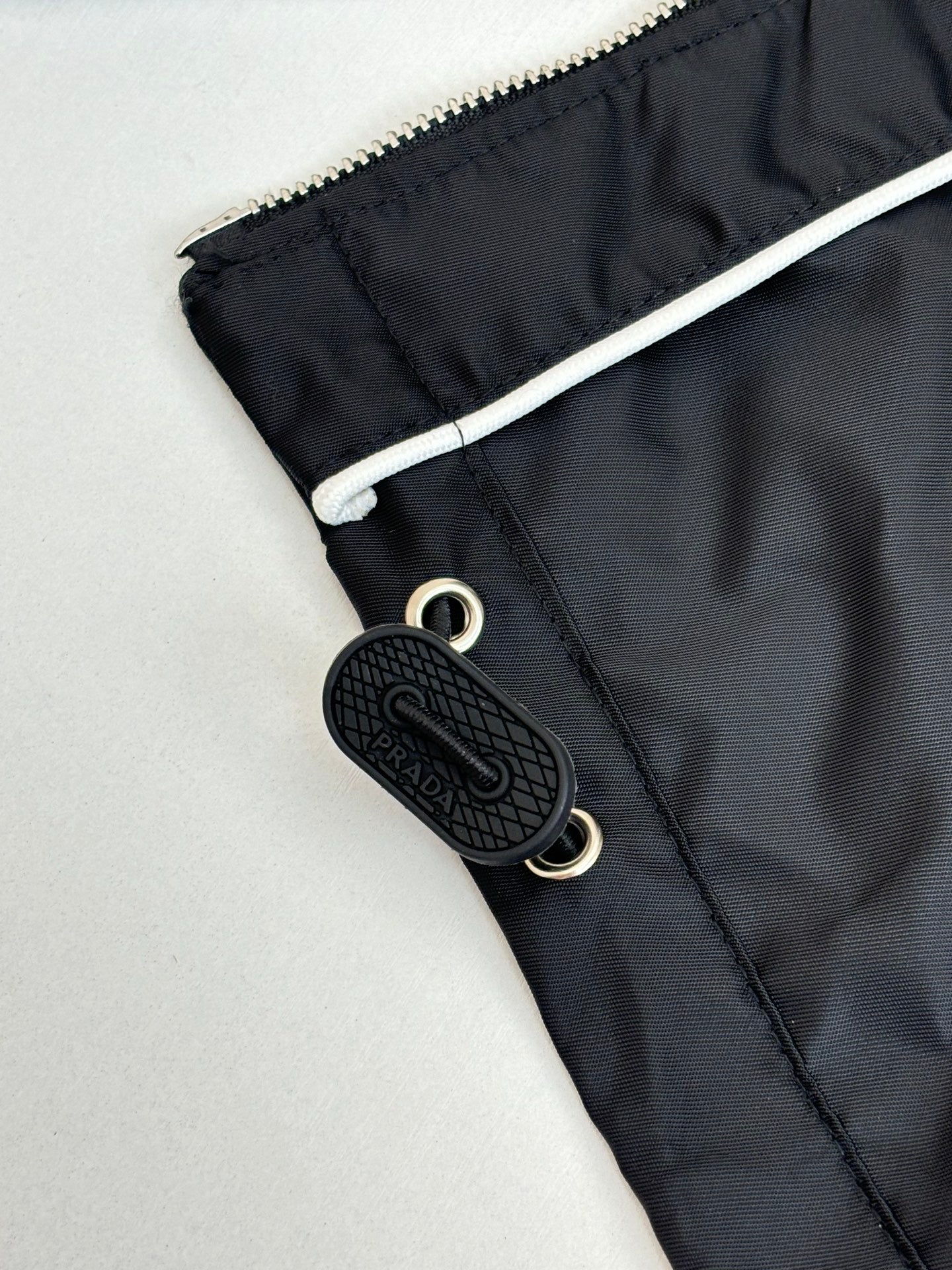 Prada black jacket pocket detail with snap closure and black logo keychain tag