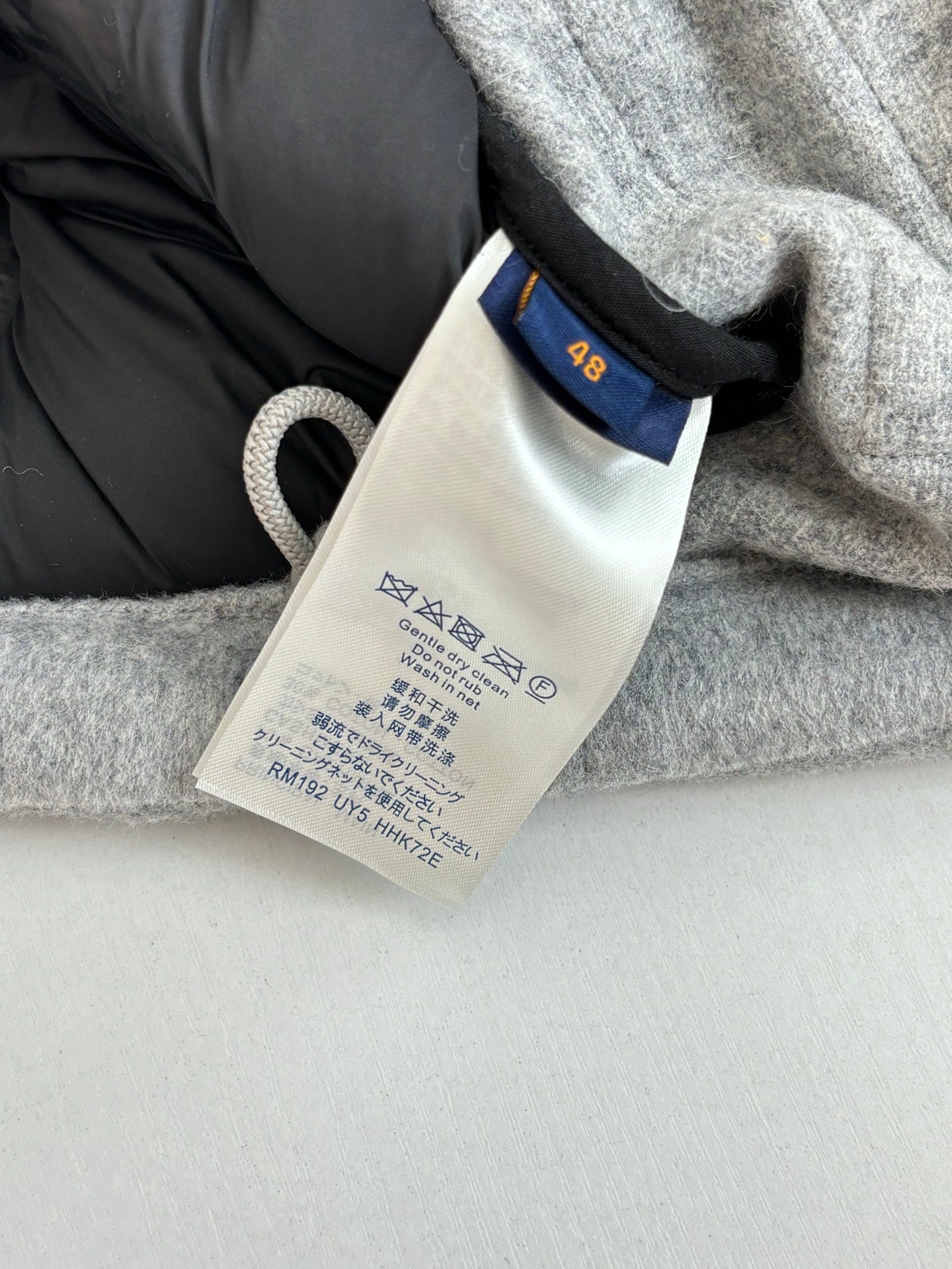 Long coat neck label and care tag on grey fabric