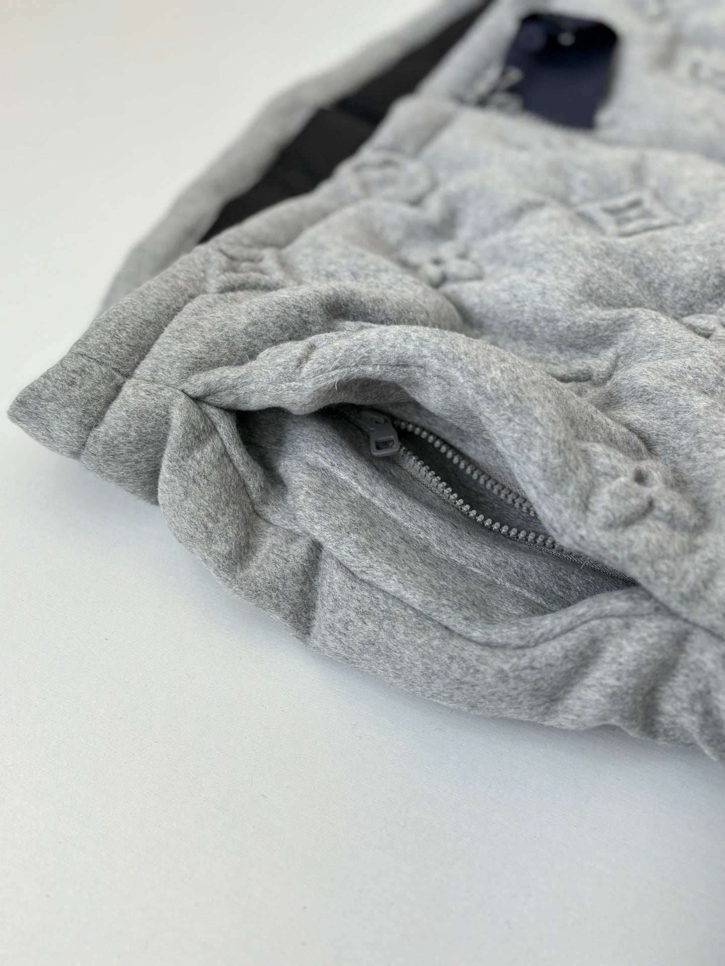 Light gray Louis Vuitton monogram jacket fabric fold with zipper close-up
